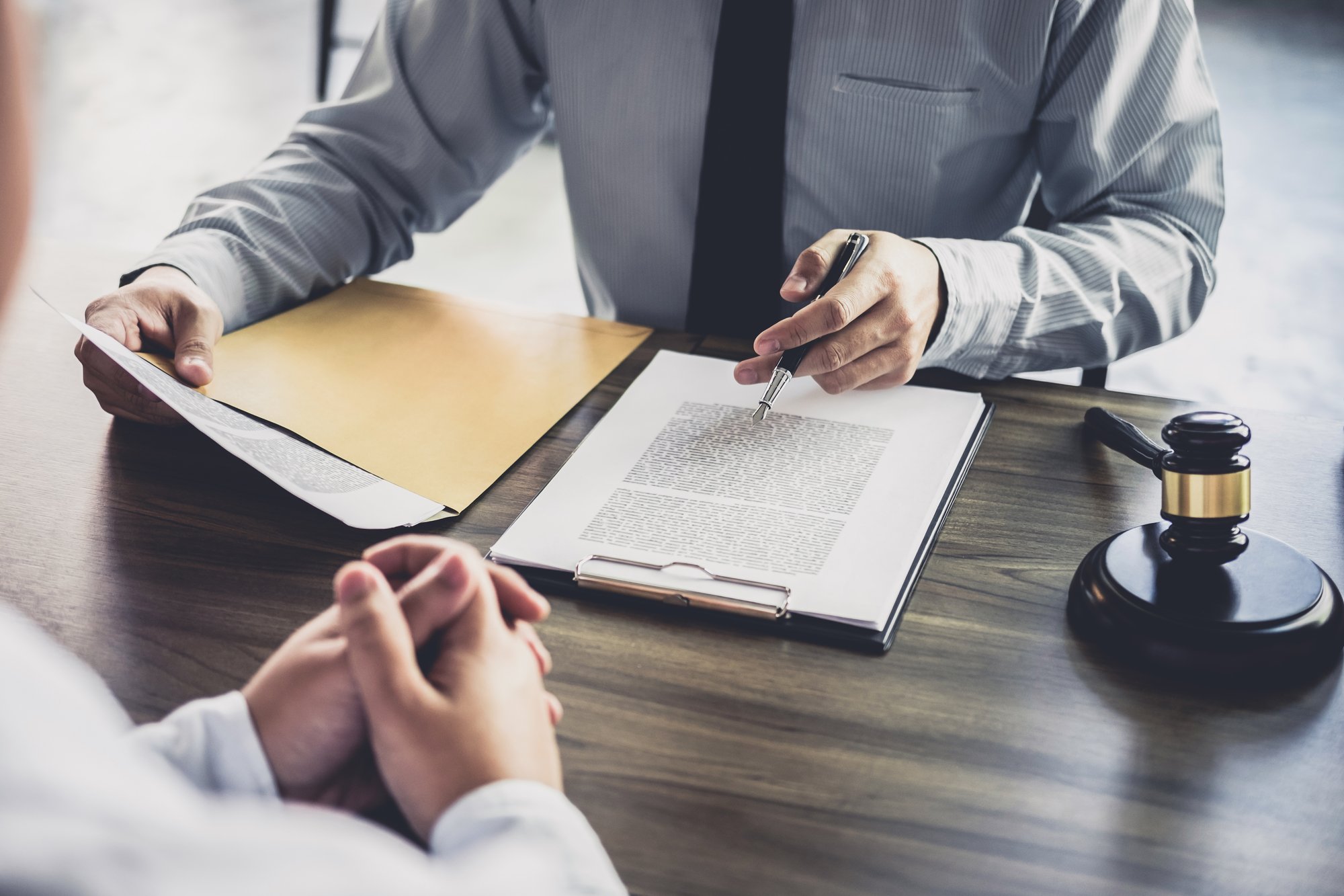 Legal professional reviewing administrative hearing documents with a client during a defense consultation.