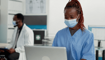 female doctor looking at a laptop and another doctor in the background