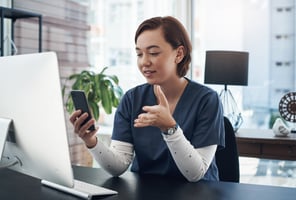 woman doctor holding a phone in front of her and talking