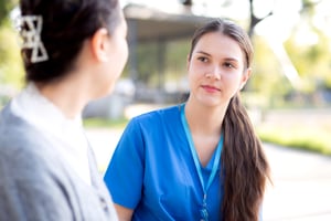 Female doctor in scrubs looking at patient listening