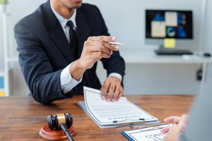 attorney holding a pen and pointing it with a gavel